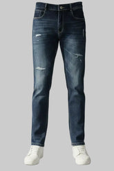 Front view of a model wearing Color Hunt men’s dark blue snow acid wash jeans with subtle distressed details on the thighs and white streetwear sneakers.